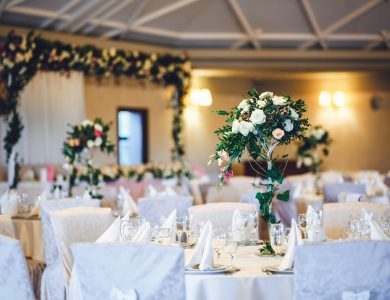 Restaurant hall with tables decorated with tall vases with roses